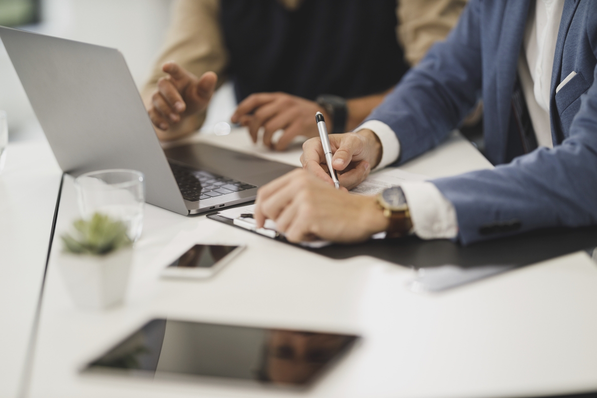 Free close up of two people hands, signing documents with laptop on table in office image, public domain CC0 photo.